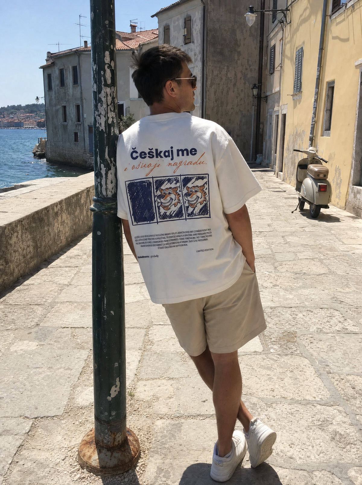 Češkaj me T-Shirt von Good Willy, getragen von einem Mann an einer Altstadtpromenade, Rückansicht (KI-generiert)