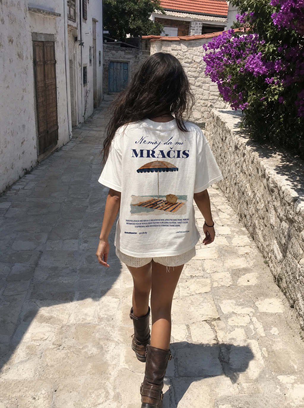 Nemoj da mi mračiš T-Shirt von Good Willy, getragen von einer Frau in einer Gasse mit Blumen, Rückansicht (KI-generiert)