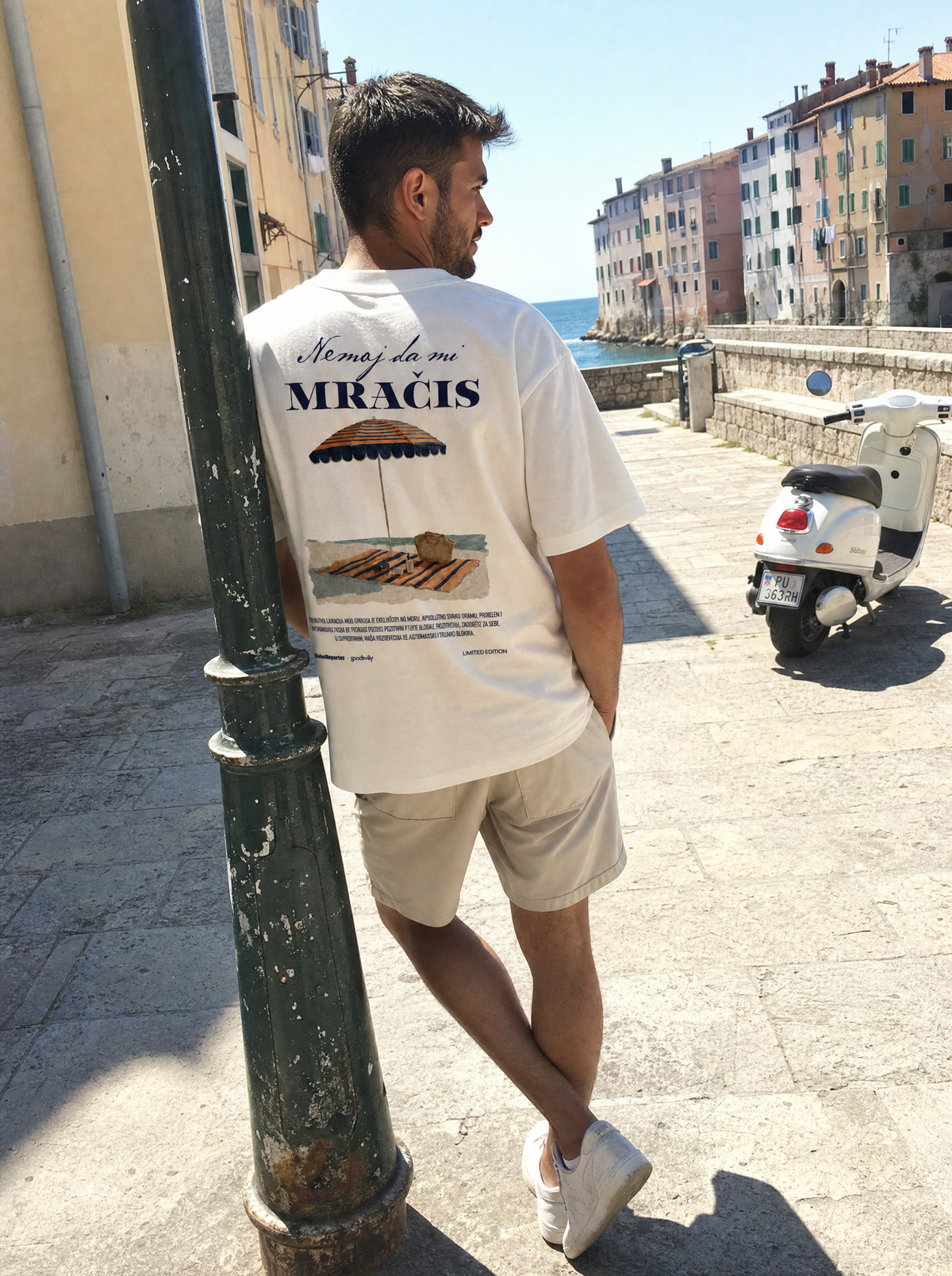 Nemoj da mi mračiš T-Shirt von Good Willy, getragen von einem Mann an einer Hafenpromenade, Rückansicht (KI-generiert)